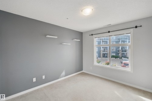 Neutral tone walls, carpet flooring, a single window, and a ceiling-mounted light fixture - #208 16035 132 St Nw, Edmonton, AB 