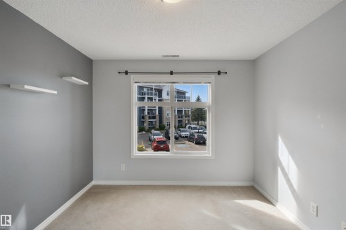 Neutral toned walls, recessed ceiling light, carpet flooring, window with white trim, and white floating shelves - #208 16035 132 St Nw, Edmonton, AB 