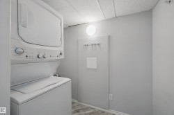 Stackable washer and dryer, light gray wall color, wood-finish flooring, and round wall-mounted light fixture - 