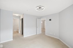 Spacious room with light-toned carpet flooring, a contemporary ceiling light fixture, and a mirrored closet door - 