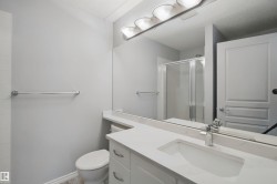 Vanity with an integrated sink, polished chrome faucet, expansive wall-mounted mirror, and overhead vanity lighting - 