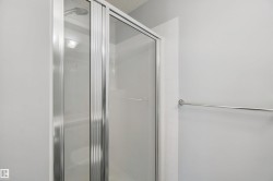 Shower enclosure with sliding glass doors, chrome hardware, and a white tiled surround - 