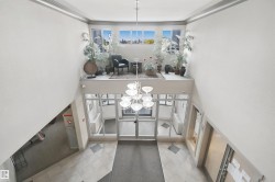Two-story foyer featuring an overhead chandelier, a glass-paneled entry, and a second-level landing with multiple windows - 