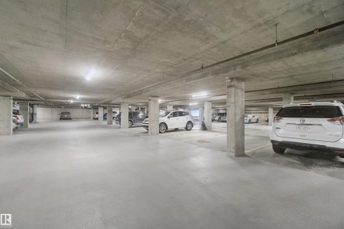 Underground parking area featuring concrete flooring, concrete columns, concrete ceiling, and integrated lighting - #208 16035 132 St Nw, Edmonton, AB 