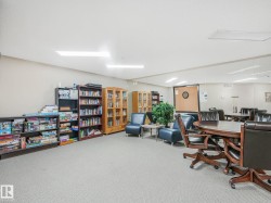 Spacious common room featuring carpet flooring, built-in shelving, recessed lighting, and a dartboard - 