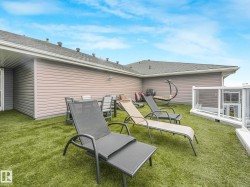 Rooftop patio with artificial turf, glass panel railing, and horizontal siding on the building's exterior - 