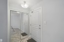 Mirrored sliding closet doors, wood-finish flooring, white paneled door, and flush-mount ceiling light - #208 16035 132 St Nw, Edmonton, AB 