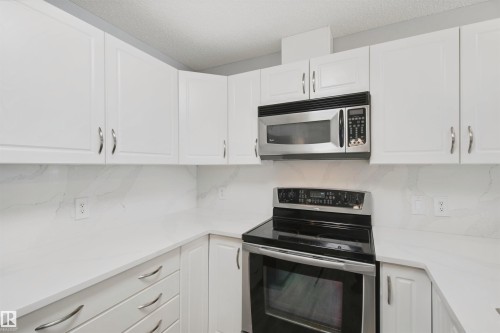 White cabinetry with chrome hardware - #208 16035 132 St Nw, Edmonton, AB 