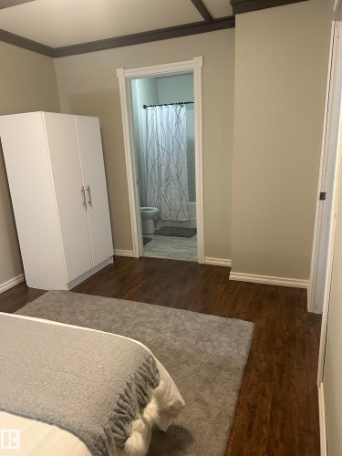Wood-finish flooring throughout, with a recessed doorway leading to a bathroom featuring a shower-over-tub combination - 35 Hudson Cove, Spruce Grove, AB 