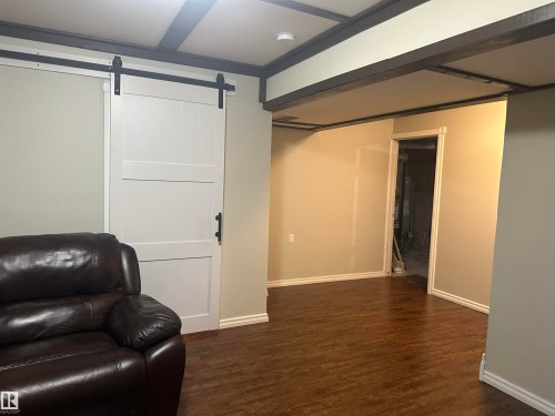 Wood-finish flooring, white trim, and a white barn door with black hardware - 35 Hudson Cove, Spruce Grove, AB 
