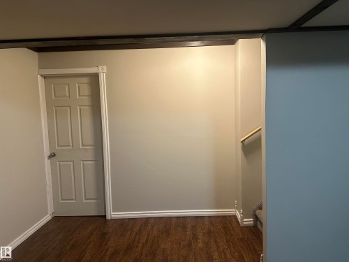 Wood-finish flooring, paneled interior door, light neutral wall paint, white trim, and a wood handrail - 35 Hudson Cove, Spruce Grove, AB 