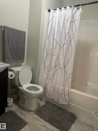 Tub/shower combination with a white surround, toilet, and wood-finish flooring - 35 Hudson Cove, Spruce Grove, AB 