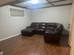 Wood-finish flooring with white baseboards, a window with white trim, and a ceiling light fixture - 