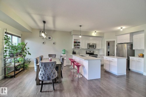 Modern kitchen with white cabinetry, stainless steel appliances, a center island, and an extended breakfast bar - 35 Hudson Cove, Spruce Grove, AB 