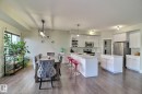Modern kitchen with white cabinetry, stainless steel appliances, a center island, and an extended breakfast bar - 35 Hudson Cove, Spruce Grove, AB 