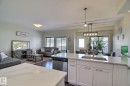 Kitchen island with a double basin stainless steel sink, white shaker cabinetry, stainless steel dishwasher, and light-toned countertops - 35 Hudson Cove, Spruce Grove, AB 