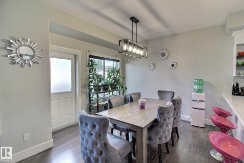 Dining area featuring wood-finish flooring, a rectangular light fixture, and a window with blinds - 35 Hudson Cove, Spruce Grove, AB 