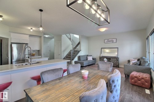 Open-concept living area with a contemporary kitchen, stainless steel appliances, and a central island with integrated sink - 35 Hudson Cove, Spruce Grove, AB 
