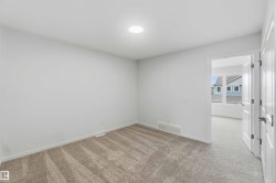 Recessed ceiling lighting, neutral tone carpet, white interior door, and white trim - 