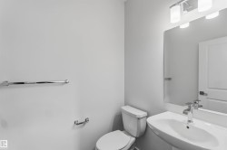 Pedestal sink with chrome faucet, toilet, wall-mounted mirror, and vanity lighting fixture - 