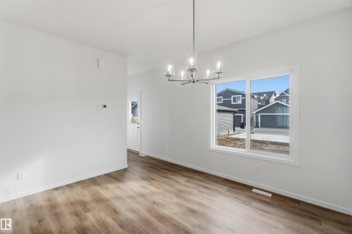 Wood-finish flooring, white walls, and a contemporary chandelier - 5733 Hawthorn Common Sw, Edmonton, AB 