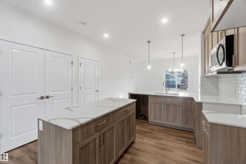 Kitchen with wood-finish flooring, light-toned cabinetry, white countertops, and subway tile backsplash - 5733 Hawthorn Common Sw, Edmonton, AB 