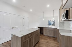 Kitchen with wood-finish flooring, light-toned cabinetry, white countertops, and subway tile backsplash - 