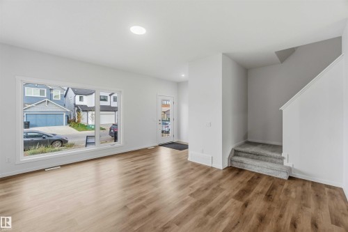 Open-concept living space featuring wood-finish flooring, recessed lighting, and a large picture window - 5733 Hawthorn Common Sw, Edmonton, AB 
