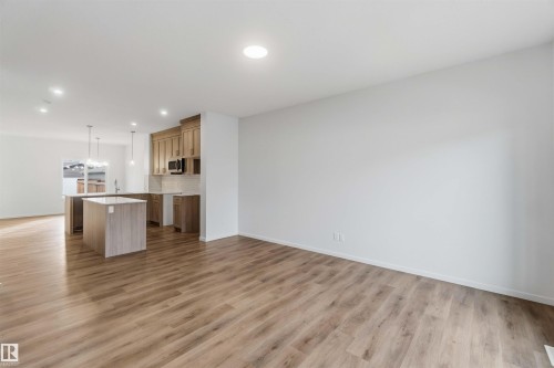 Open-concept design featuring wood-finish flooring, recessed lighting, and a kitchen island with pendant lighting - 5733 Hawthorn Common Sw, Edmonton, AB 