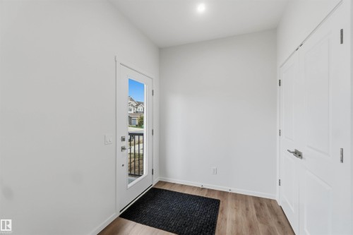Entryway featuring wood-finish flooring, white walls, and a full-light entry door - 5733 Hawthorn Common Sw, Edmonton, AB 