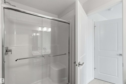 Frameless glass shower enclosure with chrome hardware, integrated shower bench, and subway tile accents - 5733 Hawthorn Common Sw, Edmonton, AB 