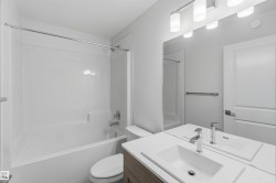 Bathroom featuring a white bathtub, integrated shower, and a vanity with a rectangular sink - 