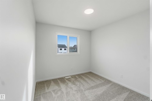 Bright interior space with a window, recessed ceiling light, and neutral-toned carpeting - 5733 Hawthorn Common Sw, Edmonton, AB 