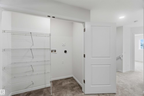 Laundry area featuring wire shelving, utility hookups, and wood-finish flooring - 5733 Hawthorn Common Sw, Edmonton, AB 