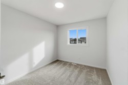 Recessed ceiling lighting, white interior walls, carpeted flooring, and a white-framed window - 