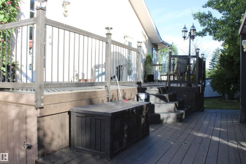 Multi-level outdoor deck featuring dark wood-finish decking and railing, built-in staircase, and exterior wall lanterns - 3815 41 Street Nw, Edmonton, AB 