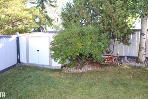 Storage shed with double doors, perimeter fencing, mature landscaping, and a built-in bench - 3815 41 Street Nw, Edmonton, AB 