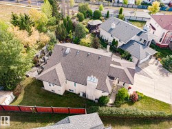 Expansive property featuring a multi-level roofline, extensive paved driveway, established landscaping, private rear patio with a pergola, and a visible adjacent property with a separate gazebo structure - 