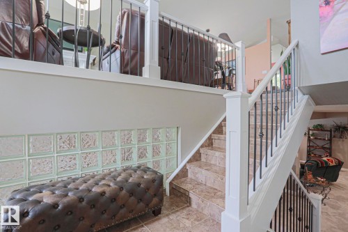 Staircase with tile treads and risers, white newel posts, and black wrought iron balusters - 3815 41 Street Nw, Edmonton, AB 