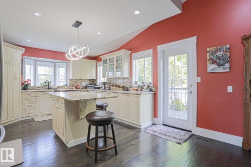 Kitchen featuring dark wood-finish flooring, white cabinetry, a center island with a light-toned countertop, and a bay window - 3815 41 Street Nw, Edmonton, AB 