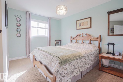 Wall-to-wall carpeting, wood bed frame, wood-framed mirror, and a decorative ceiling light fixture - 3815 41 Street Nw, Edmonton, AB 
