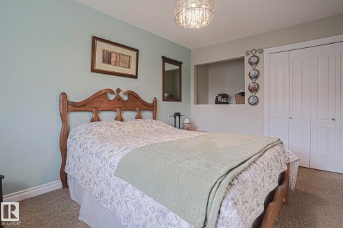 Recessed wall niche, textured carpeting, white bi-fold closet doors, decorative crystal chandelier, light-toned wall paint - 3815 41 Street Nw, Edmonton, AB 