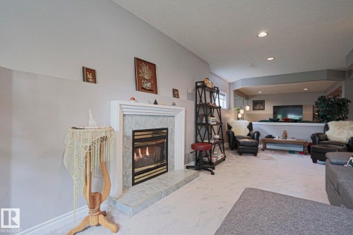 Fireplace with a tile surround and hearth, recessed lighting, and a partial wall separating spaces - 3815 41 Street Nw, Edmonton, AB 