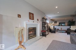 Fireplace with a tile surround and hearth, recessed lighting, and a partial wall separating spaces - 