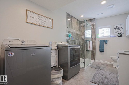 Full bathroom featuring a glass-enclosed shower with tile surround, a single toilet, and a window with blinds - 3815 41 Street Nw, Edmonton, AB 
