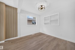 Wood-finish flooring, accent slatted wall, recessed window, built-in shelving, and a semi-flush mount light fixture - 