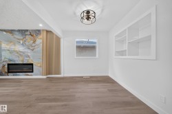 Built-in electric fireplace with a decorative surround, wood-finish flooring, recessed lighting, and a built-in shelving unit - 