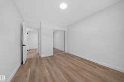 Wood-finish flooring, white walls, and a ceiling-mounted light fixture - 