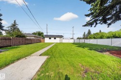 Expansive rear yard featuring a concrete pathway, detached garage, and a combination of wood and chain-link fencing - 