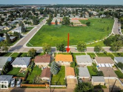 Residential property with a distinct orange-toned roof, front yard with mature tree, and a detached garage - 